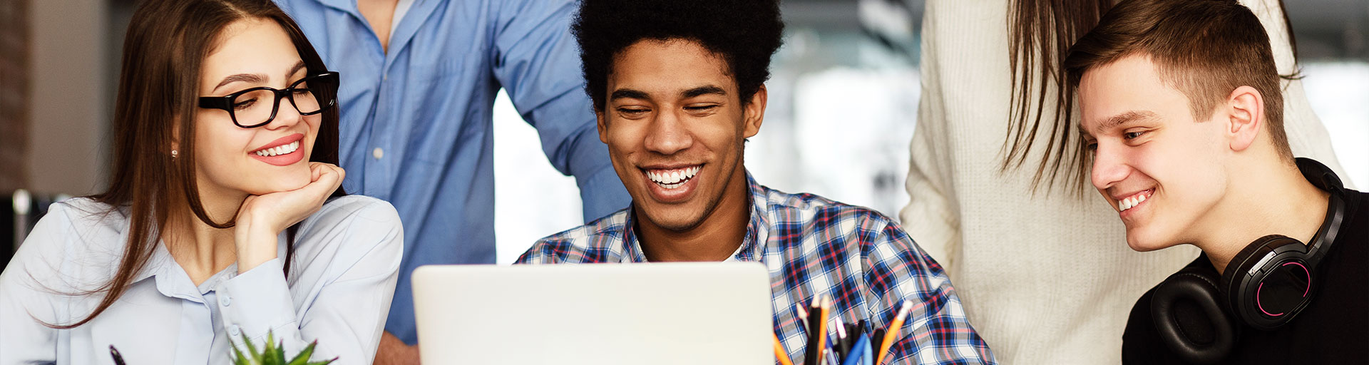 three students looking at laptop smiling