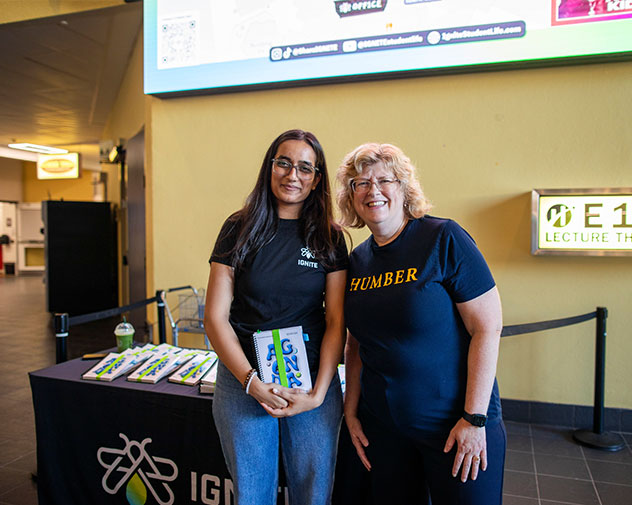 student and president in front of a IGNITE table