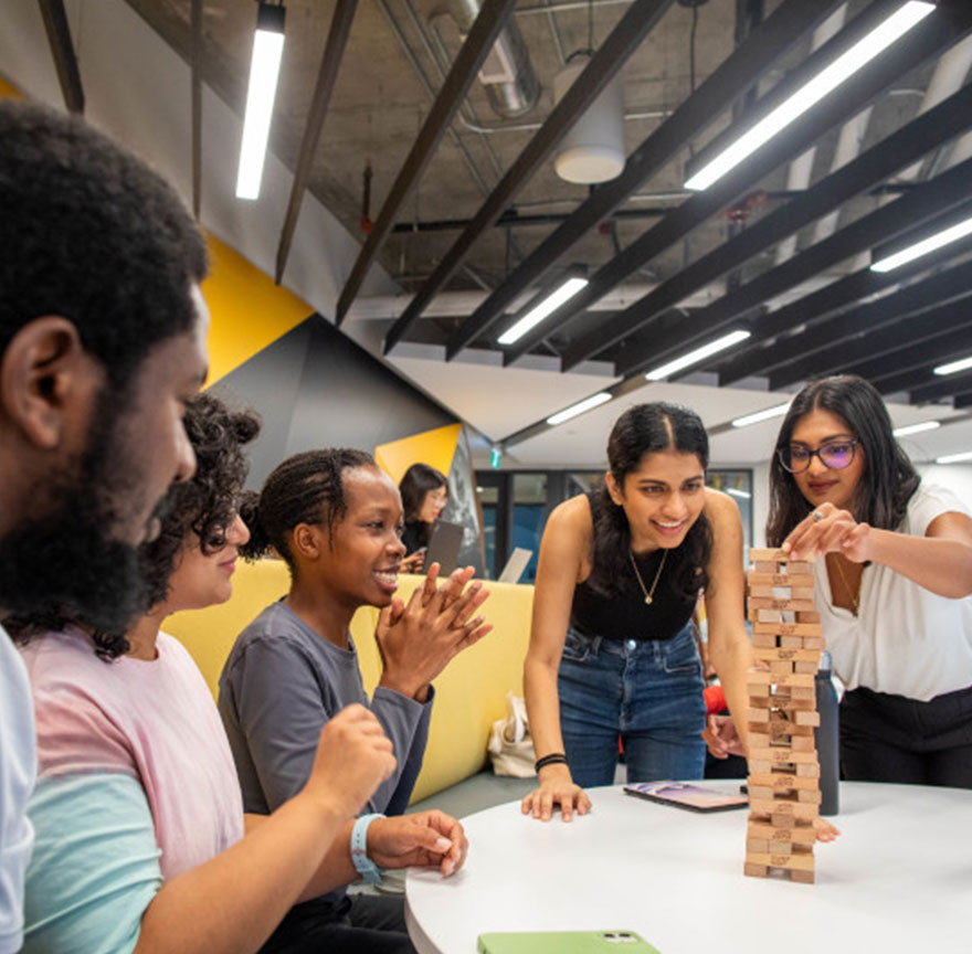 group of students sitting at a table playing jenga