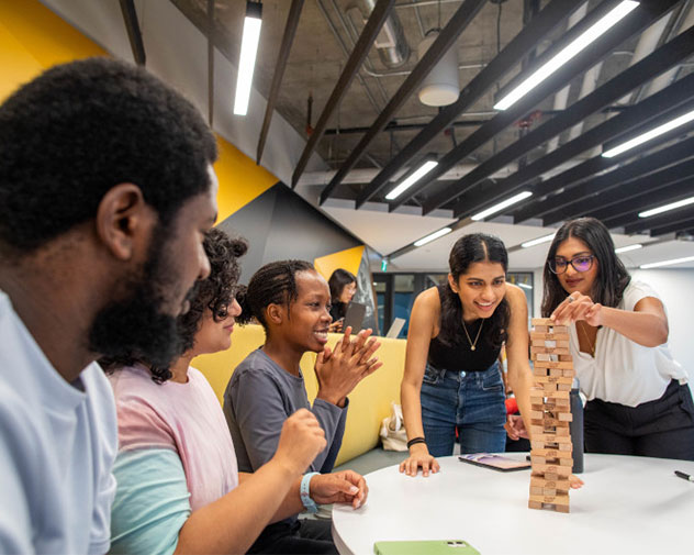 group of students sitting at a table playing jenga