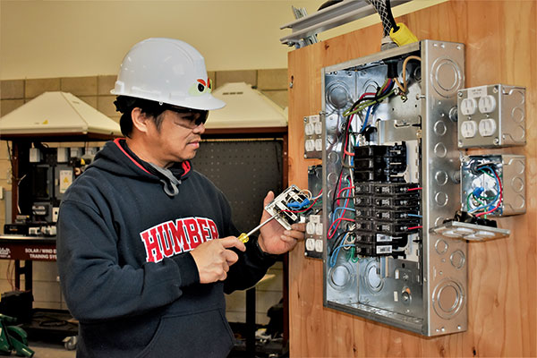 Man in helmet working on electric panel