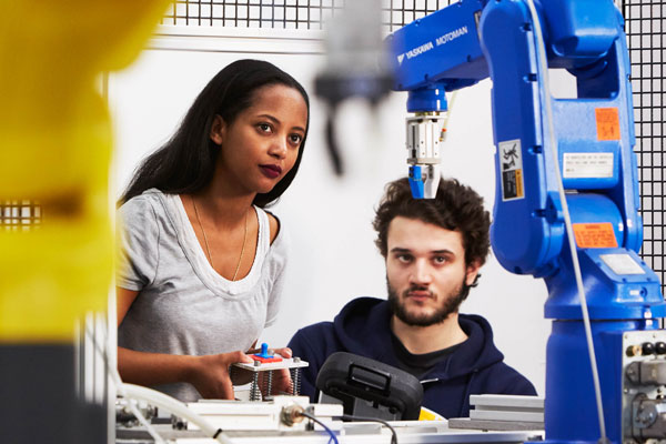 two people controlling robotic arms