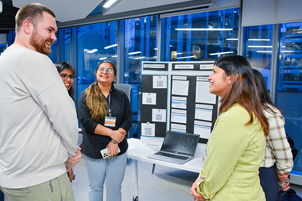 people standing by a presentation table smiling