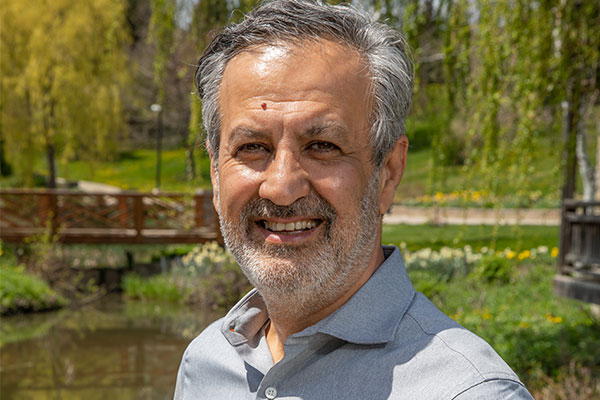 A professional headshot image of Dr. Farzad Rayegani standing outdoors and smiling