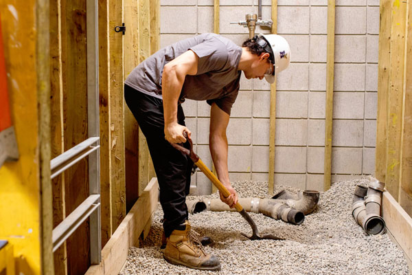 Student digging gravel inside plumbing lab