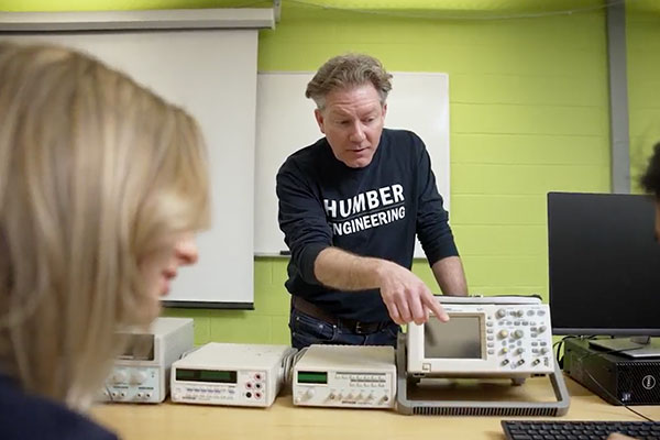 ChatGPT said: Instructor pointing at lab equipment while teaching engineering students