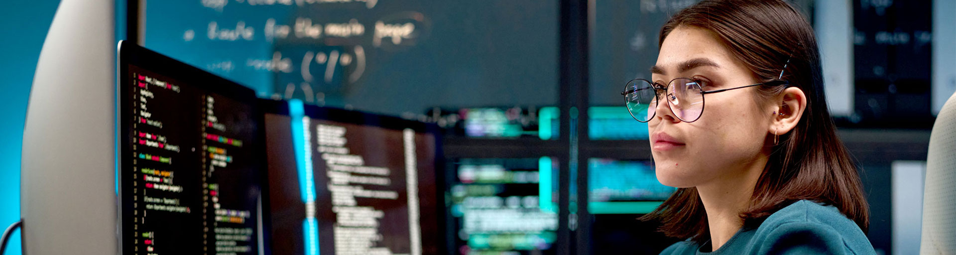worker focused at a computer station, is coding with multiple screens displaying programming code