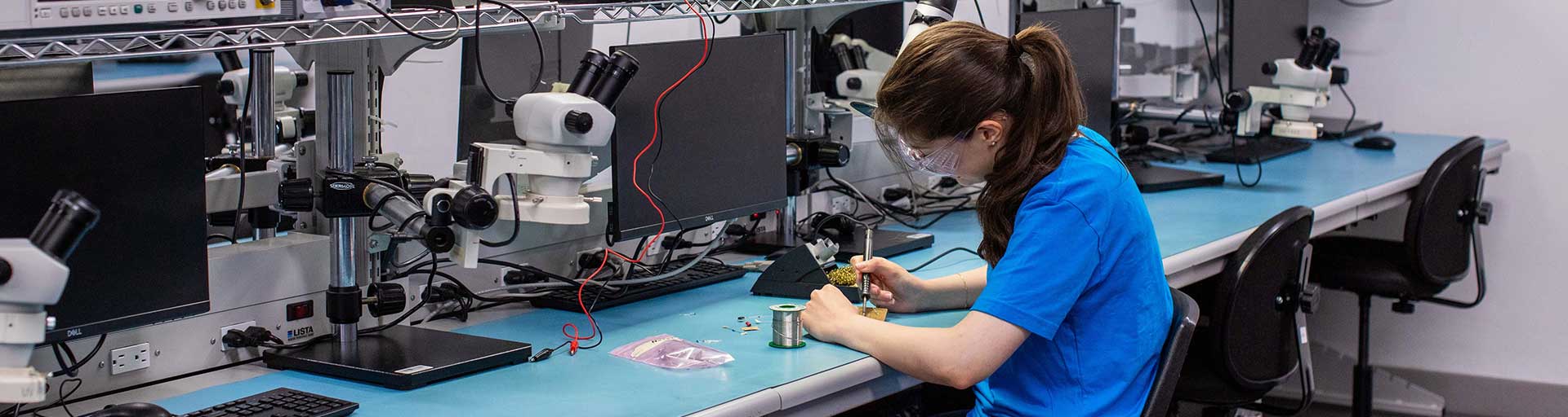 female sitting at desk soldering