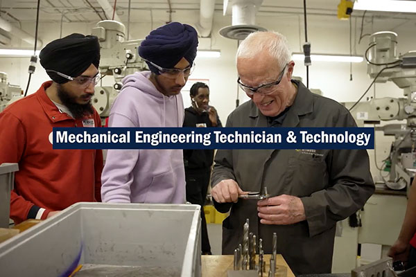 Instructor showing metal tool to students in a mechanical workshop