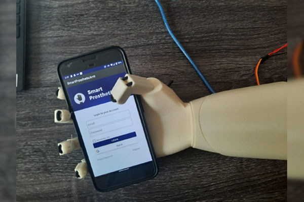 prosthetic arm holding a cell phone with the prosthetic arm control app on its screen