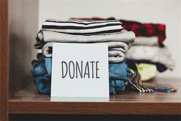 Folded up clothes on a shelf with a card that says "Donate" in front
